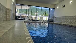 a swimming pool in a building with chairs in it at New Milan Mountain Ponoramic Hotel, with indoor heated swimming pool in Gabala