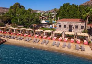 eine Reihe von Stühlen am Strand neben dem Wasser in der Unterkunft Divan Bodrum Palmira in Göltürkbükü