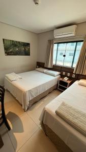 a bedroom with two beds and a window at Economy Master Hotel - Ji-Paraná in Ji-Paraná