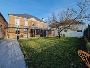 un grande edificio in mattoni con un albero nel cortile di Maison de maître avec jardin, baby-foot, proche de Cassel et plages du Nord, tout inclus ! - FR-1-510-220 a Arnèke