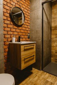 a bathroom with a brick wall and a sink and a mirror at Apartamenty Na Wzgórzu in Świeradów-Zdrój