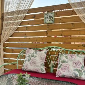 a green bench with two pillows in front of a wooden wall at Kazarma Central Suites - Apartment Complex in Egina +50 photos