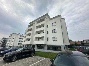 a white building with cars parked in a parking lot at Deluxe in Valea Lupului