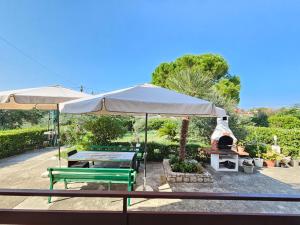 a patio with two benches and an umbrella and a grill at Apartment Milada in Banjol