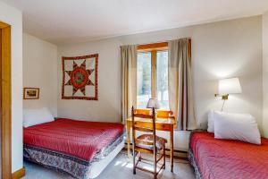 a bedroom with two beds and a desk and a window at Saltbox 12A in White River Junction