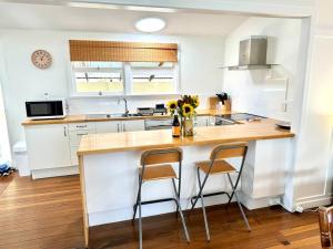 une cuisine avec un comptoir et deux tabourets sur un îlot de cuisine dans l'établissement Yamba Fishing Cottage Haven Wifi boat parking, à Yamba