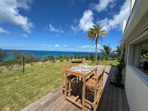 a table on a deck with a view of the ocean at Appartement Happy View - Vue mer paradisiaque - Jacuzzi in Friar's Bay