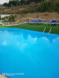 a large swimming pool with blue chairs in the background at Villa incanto in Siculiana