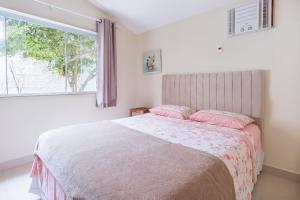 a bedroom with a bed with pink pillows and a window at Bela casa de praia sossegada no Centro de Búzios in Búzios