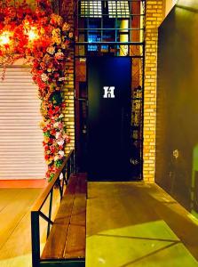 a bench in front of a black door with flowers at H70-Hostel 70 FLORIPA in Florianópolis