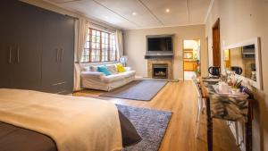 a room with a bed and a couch and a fireplace at Botanica Guest House in George +34 photos