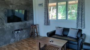 a living room with a couch and a table at Than Prawet Waterfall villa in Thong Nai Pan Noi