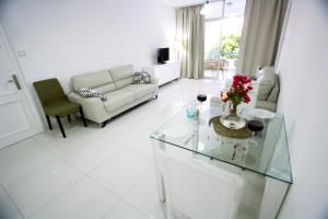 a white living room with a couch and a glass table at Pissouri Beach Apartments in Pissouri