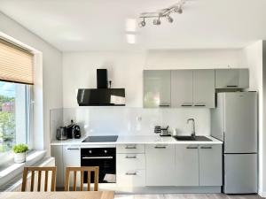 a white kitchen with a sink and a refrigerator at Przystanek Skarpa in Olsztyn +8 photos