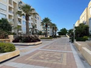 a walkway with palm trees and a building at The Yacht Apartment in Herzlia in Herzliyya B