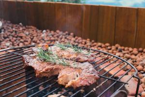 two pieces of meat cooking on a grill with vegetables at Refúgio da Montanha Brasil in Alfredo Wagner
