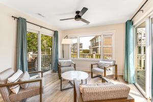 a living room with chairs and a table and windows at Family Tides by Sea Scape Properties in Wrightsville Beach