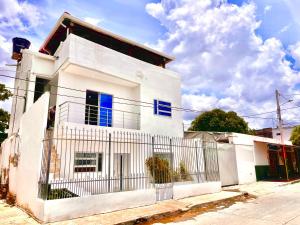 a white house with blue windows and a fence at Apartamento Exclusivo, cerca a la playa in Ríohacha