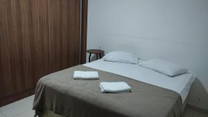 Una cama blanca con dos toallas encima. en Apartamento centro, en Ubá