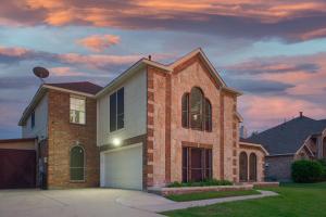 a brick house with a garage at dusk at Prestigious 5BR 3,5BA Holiday Home with Pool, Sauna, Game Room & Bar in Sachse