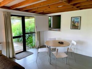 RawhitiにあるElliot Bay - Hilltop Flatの部屋の中にテーブルと椅子があるダイニングルーム