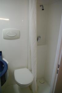 La salle de bains est pourvue de toilettes et d'un rideau de douche blanc. dans l'établissement Fasthotel Lens Noyelles Godault, à Noyelles-Godault