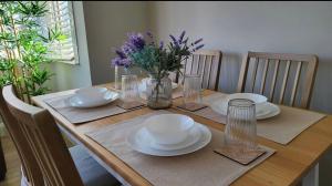 una mesa de madera con platos y cuencos y un jarrón de flores en Beautiful 4Bedroom 2Bath Wifi and Free Parking, en South Norwood
