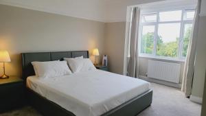 Un dormitorio con una cama con sábanas blancas y una ventana. en Beautiful 4Bedroom 2Bath Wifi and Free Parking, en South Norwood 5 fotos más