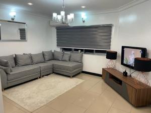 a living room with a gray couch and a television at Tao Connexus in Abuja