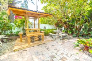 a wooden gazebo in a garden with a bench at Oceanview, in Village, 20-steps to Path of Best Beach, Tiki-Bar, Free Bikes and Paddle-boards! in Siesta Key