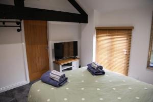 a bedroom with a bed with two pillows and a television at White Swan Cottage in Hunmanby