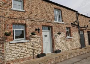 a brick building with a white door and windows at White Swan Cottage in Hunmanby