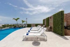 a row of white lounge chairs next to a pool at Depto ideal para tu viaje in Playa del Carmen