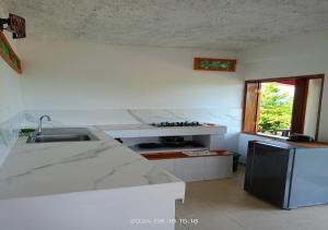 a white kitchen with a sink and a window at Posada Refugio de la Luna in Providencia