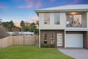 une maison avec une porte de garage blanche et une clôture dans l'établissement Andrica House - Your Southern Highlands Retreat!, à Mittagong