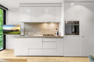 Una cocina blanca con gabinetes blancos y un fregadero. en Contemporary 1-Bed in the Heart of St Kilda, en Melbourne