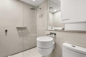 baño blanco con aseo y ducha acristalada en Contemporary 1-Bed in the Heart of St Kilda, en Melbourne 4 fotos más
