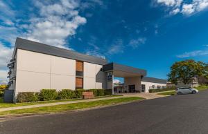 QuirindiBest Western Club Quirindi Motel的一栋白色建筑，前面停着一辆汽车