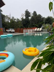 a swimming pool with two inflatable boats in it at The Caligo resort coorg in Madikeri