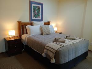 a bedroom with a bed with two night stands and two lamps at Taranaki Experience in New Plymouth