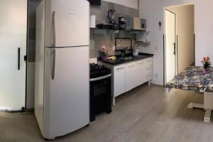 een keuken met een witte koelkast en een fornuis bij El Badan Hospedagem - Casa 3 in Olímpia