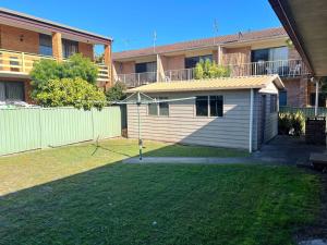 a small shed in a yard next to a building at Sutts Retreat - Bring your own linen. in South West Rocks