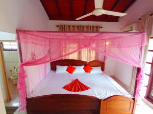 Un dormitorio con una cama con dosel y almohadas rojas. en Calm Nature Villa, en Matara