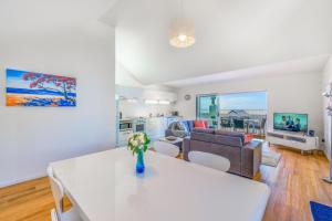 Una sala de estar con una mesa blanca y un sofá. en Palm Beach Penthouse by Waiheke Pure, en Palm Beach 3 fotos más