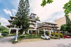 a white car parked in front of a building at Grand Diamond Hotel Yogyakarta - Formerly Grand Quallity Hotel in Yogyakarta