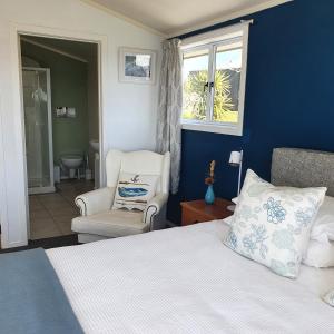 a bedroom with a bed and a chair and a window at Oneroa Bay View Apartment in Oneroa