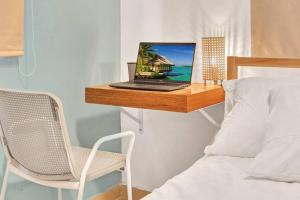 a laptop computer sitting on a wooden shelf next to a bed at OASIS Punta Cana Apartment in Punta Cana
