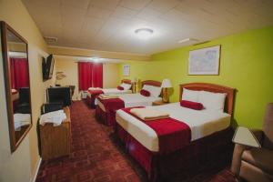 una camera d'albergo con tre letti e pareti verdi di Falls View Inn a Niagara Falls