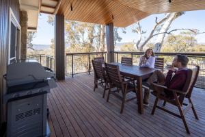 Ein Mann und eine Frau sitzen an einem Tisch auf einem Deck in der Unterkunft Creel Bay Cottages in Kalkite