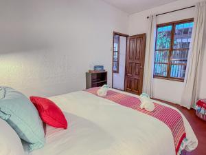 a bedroom with a white bed with red and blue pillows at Villa Dulé in Antigua Guatemala